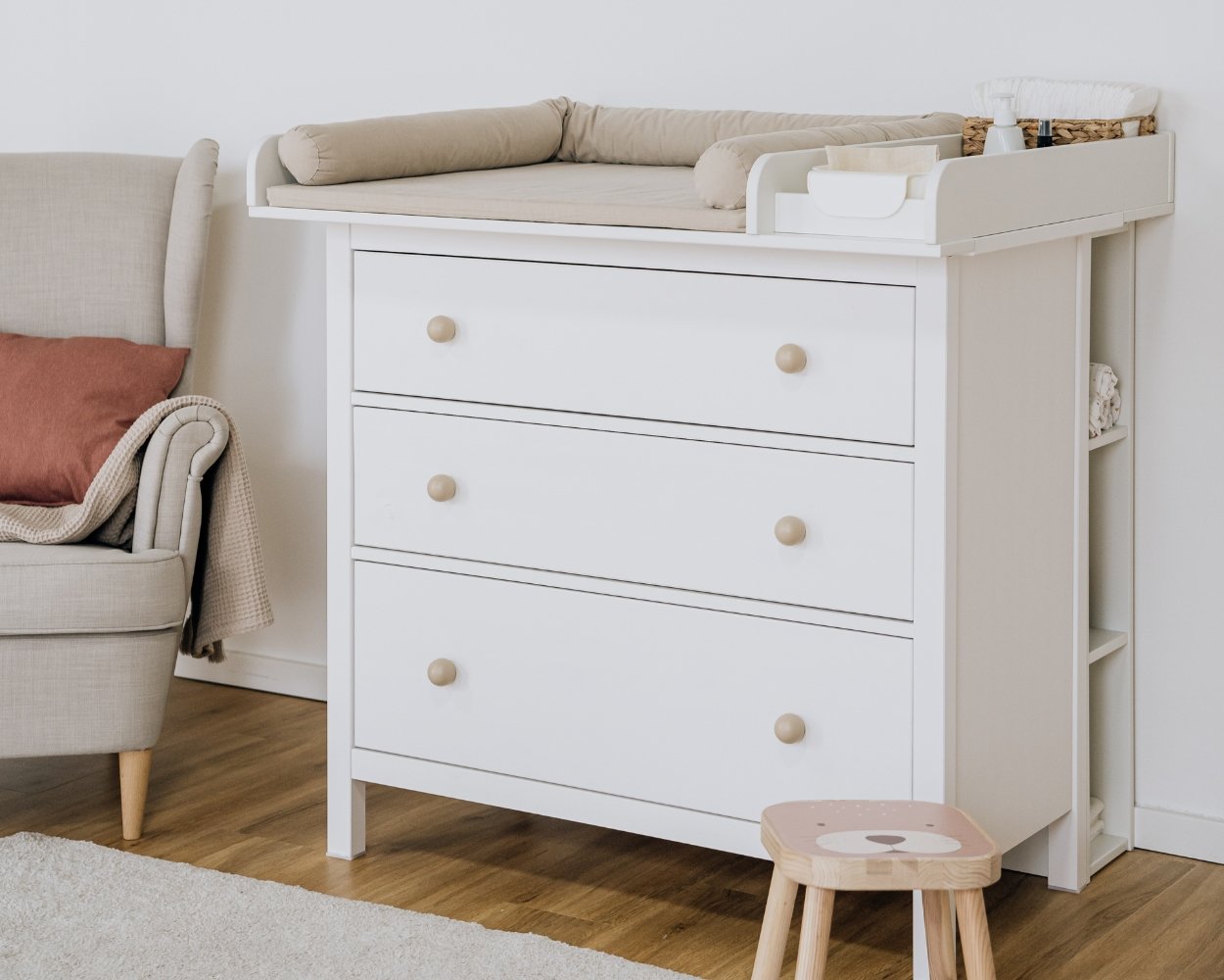 Stillsessel im Babyzimmer steht neben einer Wickelkommode mit Limmaland-Wickelaufsatz