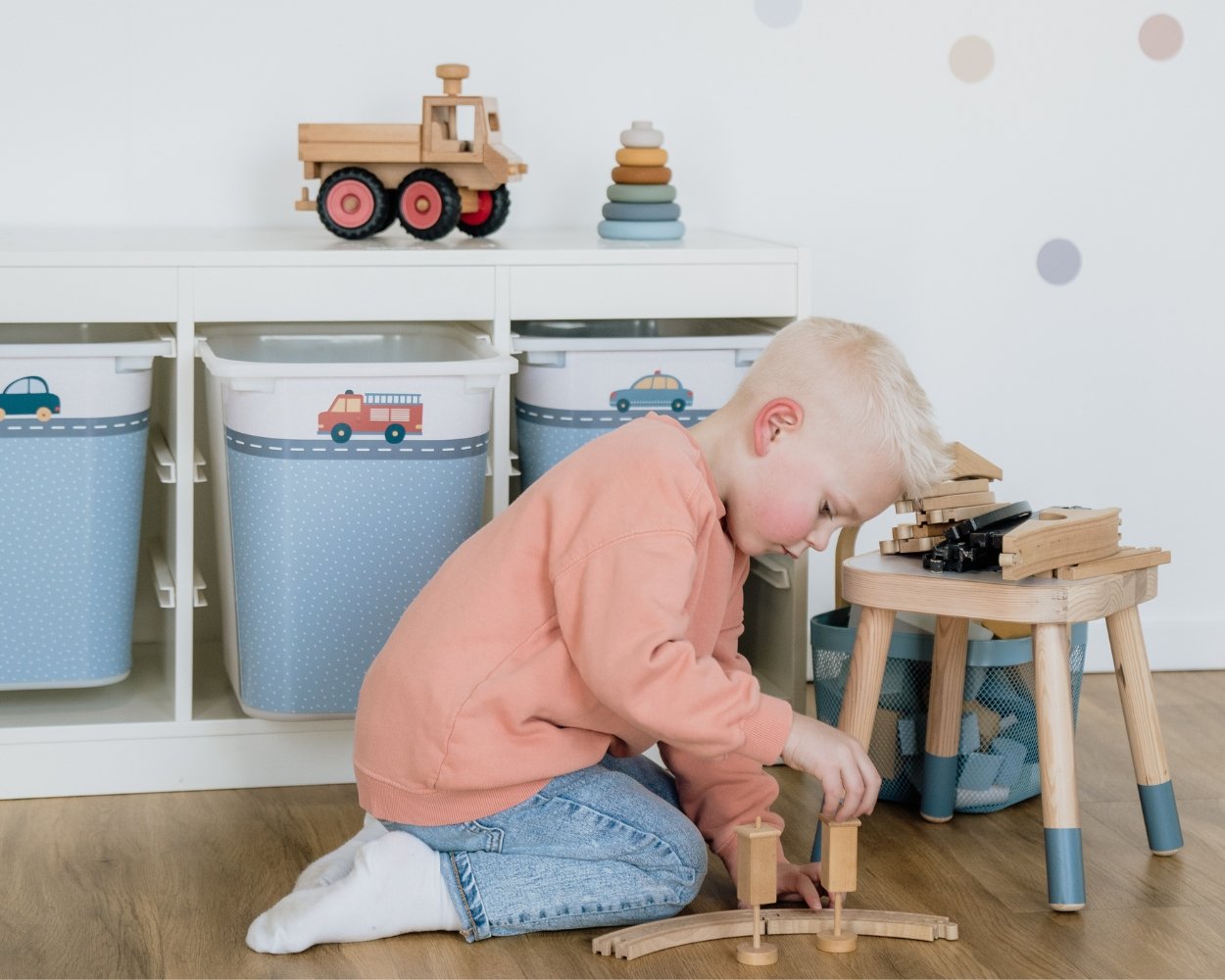 Ein Junge spielt mit Bauklötzen in seinem Kinderzimmer Jungs, im Hintergrund ein Ikea Trofast Regal mit blauer Klebefolie